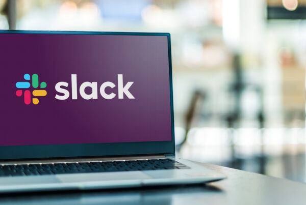 Photograph of laptop displaying logo of Slack